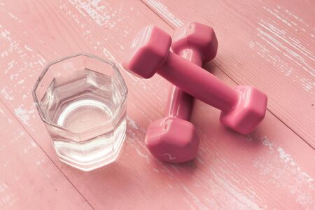 Close up of pink color dumbbell and glass of water on tableの写真素材