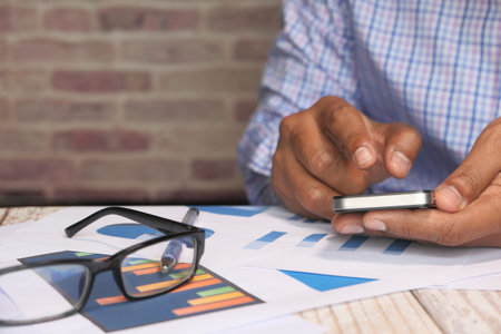 Businessman use smart phone and financial paper on desk