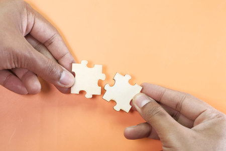 two hands trying to connect couple puzzle piece