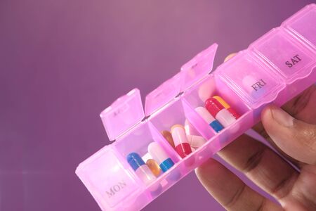 man hand holding pill box on color backgroundの写真素材