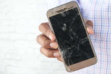 man holding smartphone with a broken screen.