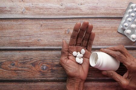 Elderly woman pouring pills from bottle on hand, top viewの写真素材