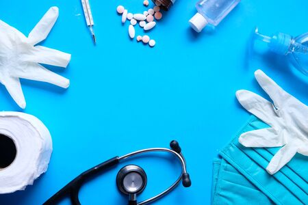 gloves with surgical face mask, pills and hand sanitizer on blue backgroundの写真素材