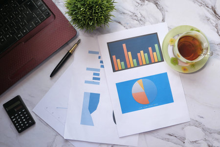 self created chart , financial charts, calculator and tea on table 