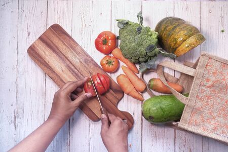 Top view of man cutting tomato on chopping board.の写真素材
