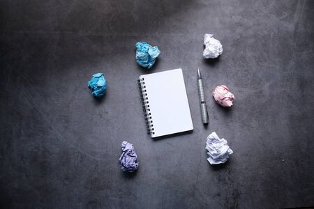 Top view of crumpled paper balls and notepad on gray background.の写真素材