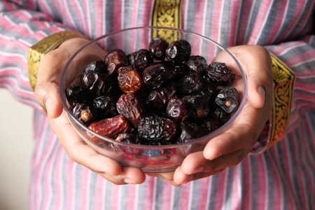 the concept of ramadan, hand holding a bowl of date fruits