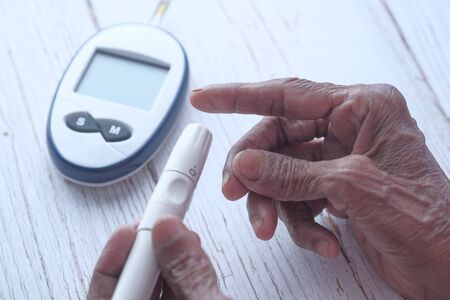 Senior women diabetic measure glucose level at homeの写真素材