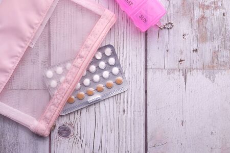birth control pills and pill box on wooden tableの写真素材