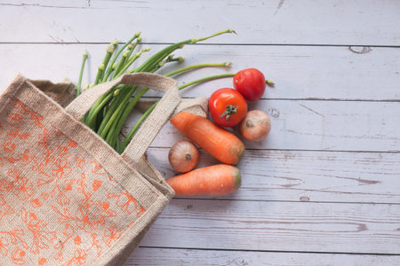 high angle view of fresh vegetables and reusable shopping bag on table.