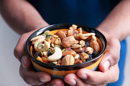 Man hand holding a bowl of Mixed nutsの写真素材