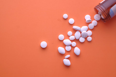 white pill spilling from container on orange background