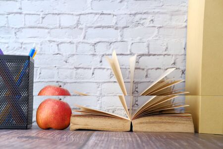 close up of apple on stack of notebooks on table.