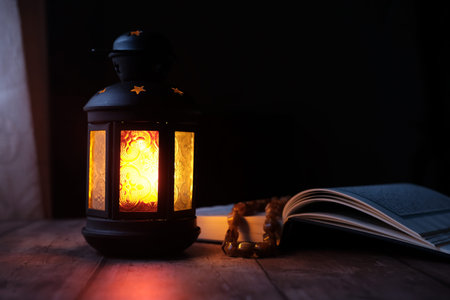 Ornamental Arabic lantern with burning candle glowing at night.