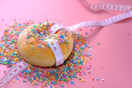 Close up of donuts and measurement tape on pink background.の写真素材
