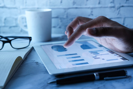 Man hand analyzing chart on digital tablet at office desk