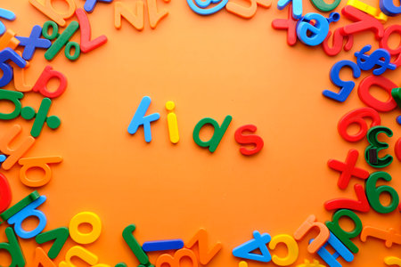 Kids words in colorful plastic letters on orange background.