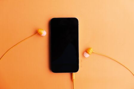 smart phone and earphone on orange background .の写真素材