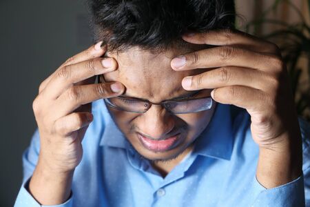 Young man frustrated and suffering headache, close upの写真素材