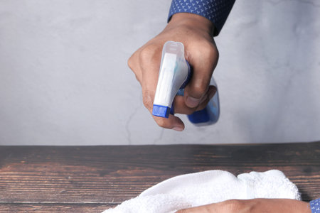 Hand holding spray bottle cleaning a table
