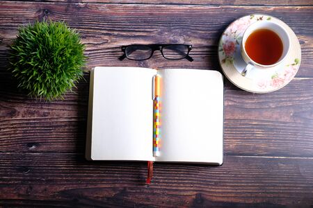 high angle view of open diary, tea and eyeglass on tableの写真素材