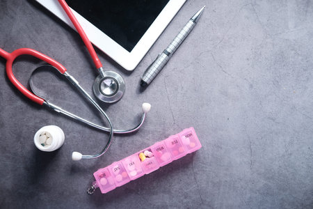 Medical Stethoscope, pills and digital tablet on black background