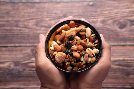 Hand holding a bowl of mixed nut top downの写真素材
