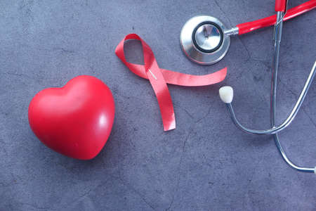 Red ribbon HIV, heart and stethoscope on black background.の写真素材
