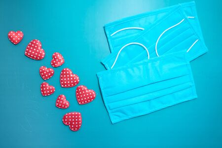 Surgical masks with heart shape and hand sanitizer on green backgroundの写真素材