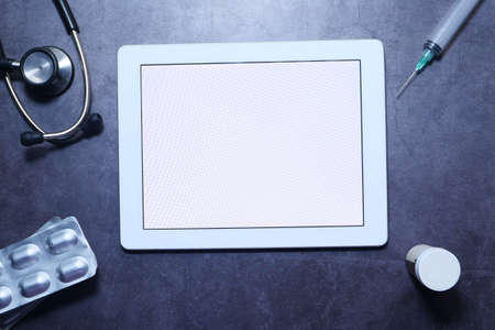 Flat composition of digital tablet, pills and stethoscope on black backgroundの写真素材