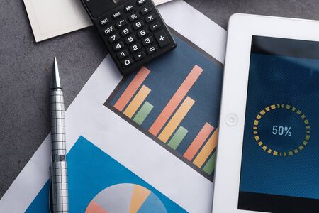 high angle view of financial charts and digital tablet on tableの写真素材