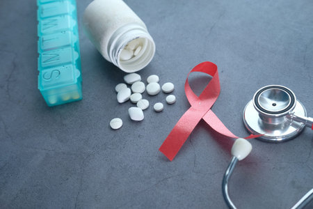 Red ribbon HIV, pills and stethoscope on black background.の写真素材
