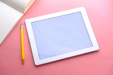 Flat composition of digital tablet and notepad on pink backgroundの写真素材