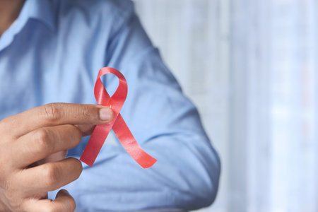 man holding red HIV ribbon with copy space