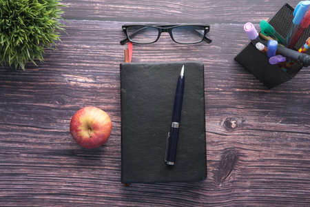 Back to school concept with apple, book and eyeglass on wooden backgroundの写真素材