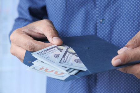 person hand putting cash in a envelope.