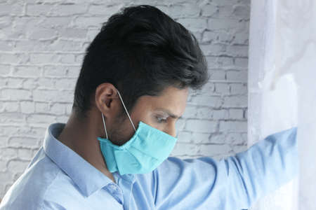 A young asian man with protective mask in face feeling sadの写真素材