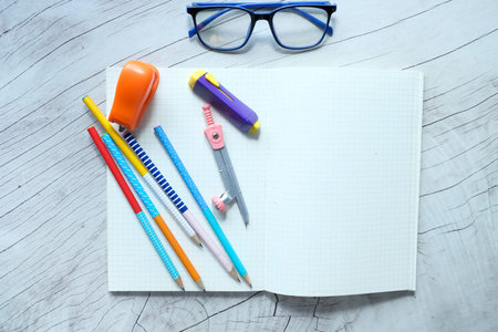 Blank notebook and school supplies on wooden table .