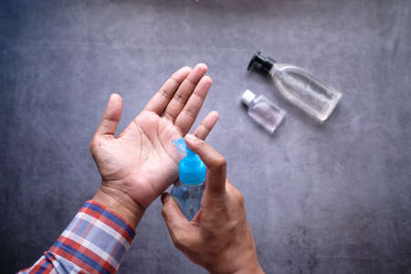 close up of man hand using sanitizer gel isolated on blackの写真素材