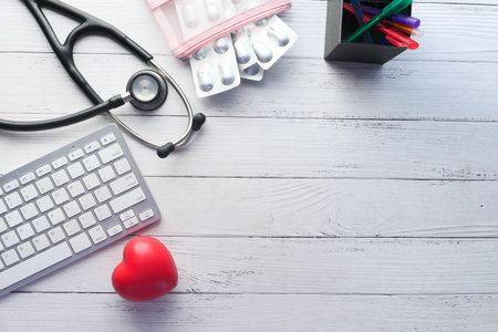 high angle view of pills , keyboard and stethoscope on clinic desk .