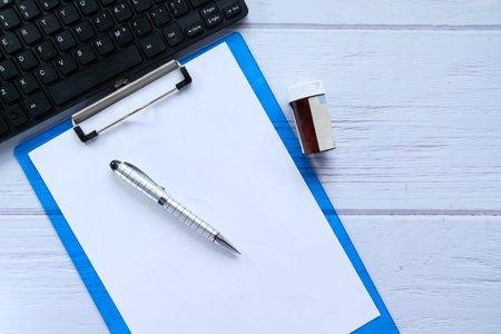 doctors workplace with container, keyboard and prescription on desk.