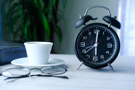 Retro alarm clock, notepad and eyeglass on wood table
