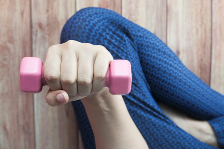 Young woman exercising with dumbbell weights top view