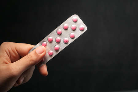women hand holding blister pack isolated on black.の写真素材