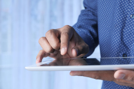 man's hand working on digital tablet at office desk, using self created chart.