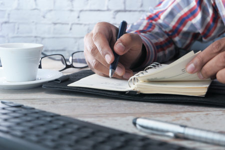 Close-up of business man hands writing on notepad
