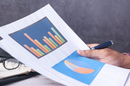 man hand with pen analyzing bar chart on paper.