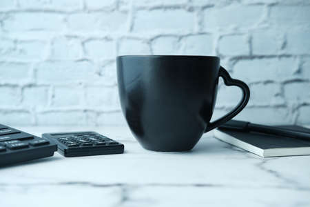 Black mug mockup with with keyboard, notebooks on table .の写真素材