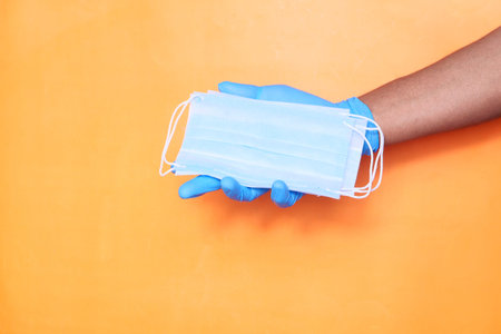 doctor hand in medical glove holding protective surgical face mask, close up