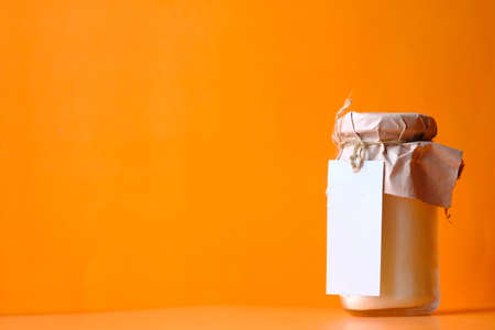 coconut oil in jar with a white label on orange background.の写真素材